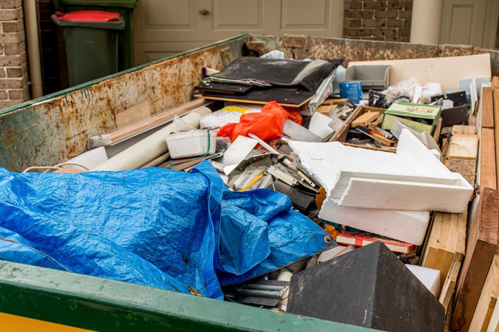 Skip bin full of household waste rubbish on the frond yard. House clean up concept